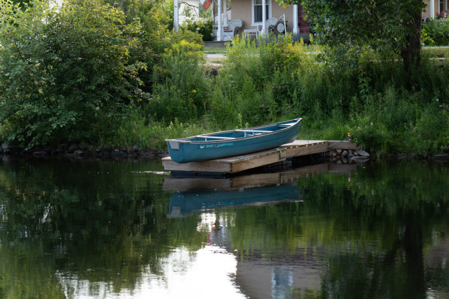 Blue canoe tied to a small wooden dock on the Gull River, Minden Ontario