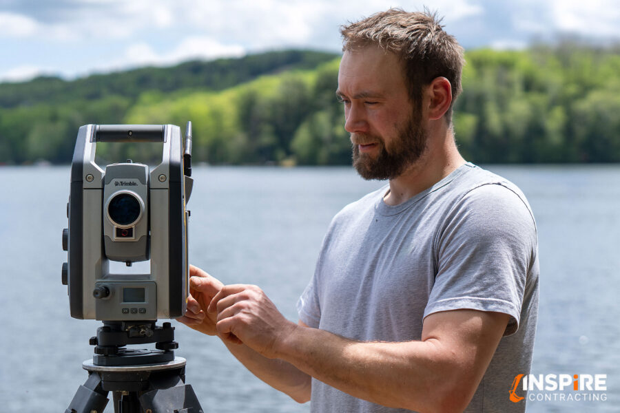 Inspire Contracting’s Tyler Hall using surveying equipment to measure elevations for a cottage construction project
